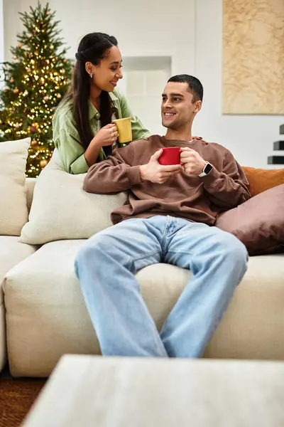 A couple shares warm drinks in their modern apartment, joyfully celebrating Christmas. — Stock Photo