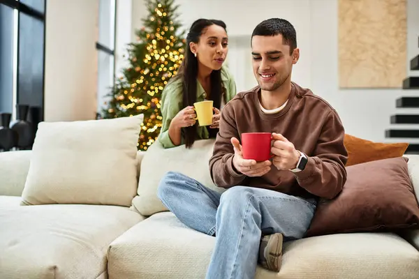 A couple shares warm drinks in their cozy, festive living room. — Stock Photo