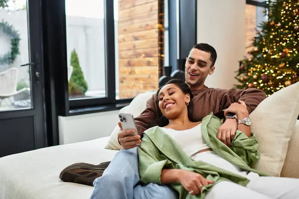 A beautiful couple relaxes on a sofa, sharing smiles while enjoying each others company. — Stock Photo