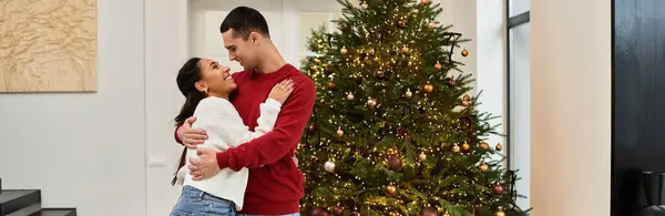 A beautiful couple embraces in a decorated living room, filled with holiday warmth and joy, banner — Stock Photo