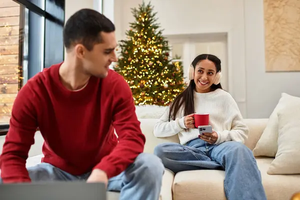 Calore e risate riempiono l'aria mentre una coppia celebra il Natale nel loro elegante spazio vitale. — Foto stock