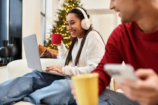 Pareja se relaja en una elegante sala de estar, bebiendo bebidas y compartiendo momentos durante la Navidad. — Stock Photo