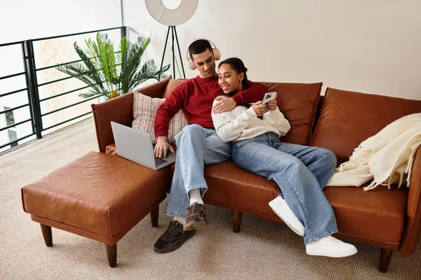 Un couple en tenue d'hiver se détend ensemble sur leur canapé à la maison. — Photo de stock