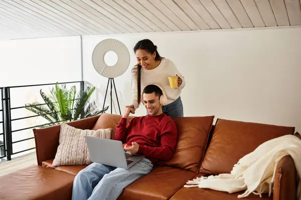Un beau couple profite d'un moment chaleureux ensemble tout en travaillant sur un ordinateur portable à la maison. — Photo de stock
