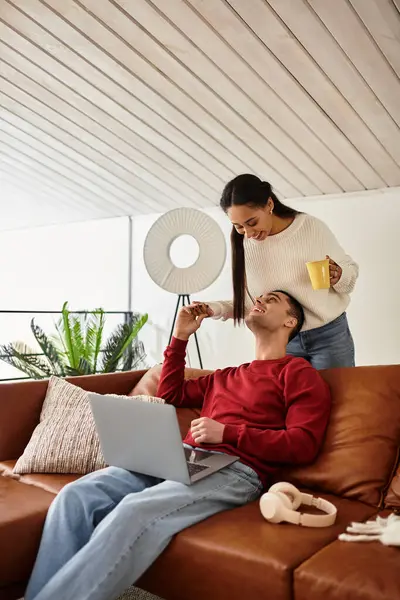 Un couple rit autour de boissons chaudes dans leur confortable appartement moderne cet hiver. — Photo de stock
