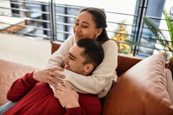 Couple jouit d'une accolade joyeuse dans leur loft élégant, entouré de chaleur hivernale et de confort. — Photo de stock
