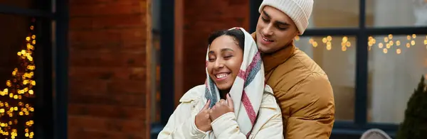Un couple jouit d'une étreinte amoureuse à l'extérieur, entouré de décorations festives et de charme hivernal, bannière — Photo de stock