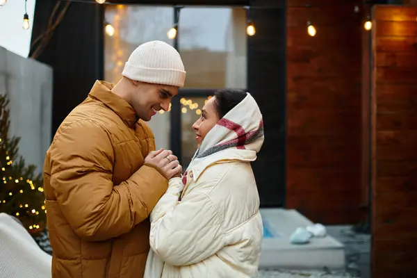 A beautiful couple enjoys a romantic moment outdoors, surrounded by festive winter decorations. — Stock Photo