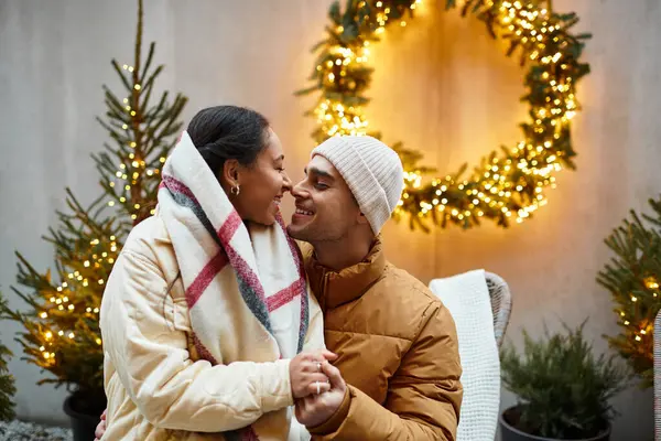 A beautiful couple shares a joyful moment outdoors, surrounded by holiday lights and decorations. — Stock Photo