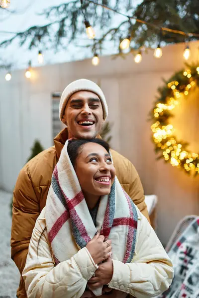 A couple enjoys each others company outdoors, surrounded by Christmas lights and decorations. — Stock Photo
