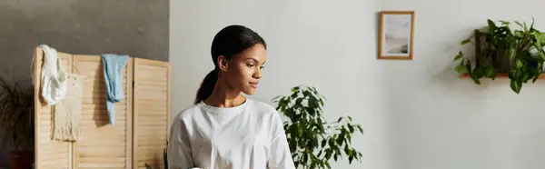A young African American woman diligently tidies her stylish apartment, radiating positivity, banner — Stock Photo