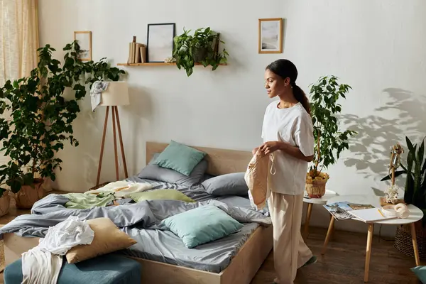 A cheerful young African American woman tidies up her modern apartment as she embraces daily chores. — Stock Photo
