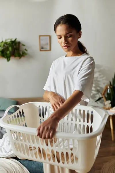 In a cozy modern apartment, a young woman organizes her laundry with focus and care. — Stock Photo