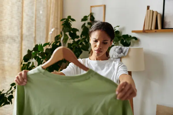 Una joven afroamericana organiza su casa, rodeada de vegetación y luz. - foto de stock