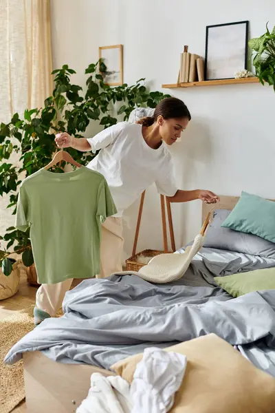 Bright and tidy apartment showcases a young woman organizing her bedding and clothes thoughtfully. — Stock Photo