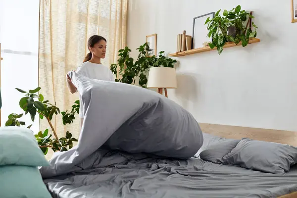 Uma jovem afro-americana arruma seu quarto, enchendo travesseiros e fazendo a cama. — Fotografia de Stock
