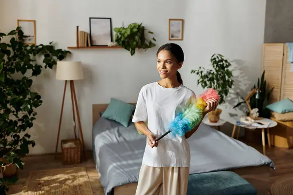 Uma jovem mulher feliz sorri enquanto limpa seu elegante apartamento. — Fotografia de Stock