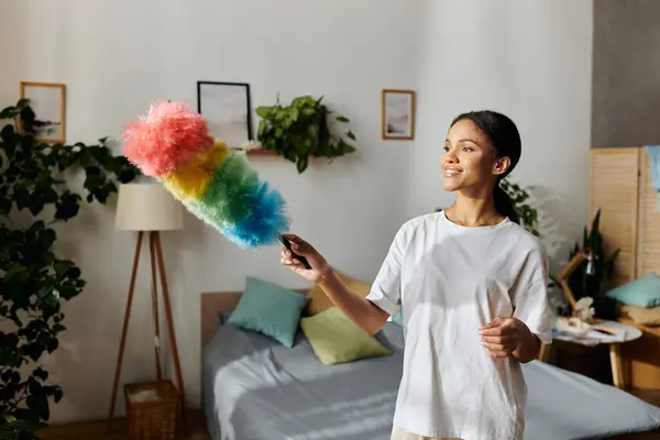 Jovem mulher alegremente polvilhar seu elegante espaço de vida, apresentando uma casa arrumada e decoração vibrante. — Fotografia de Stock