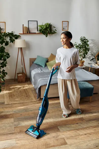 In a bright modern apartment, a young African American woman cleans the floor with care. — стоковое фото