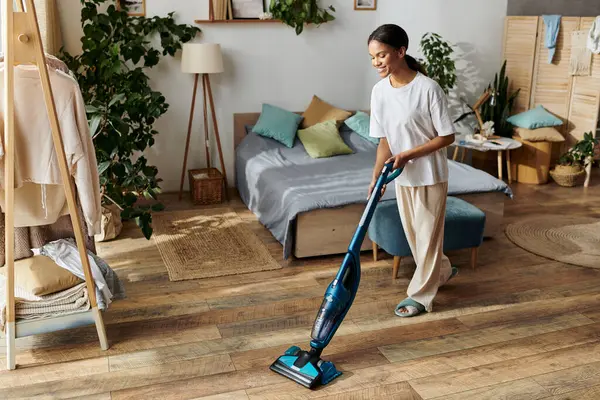 A young Black woman cleans her modern apartment, adding brightness to her home. - foto de stock