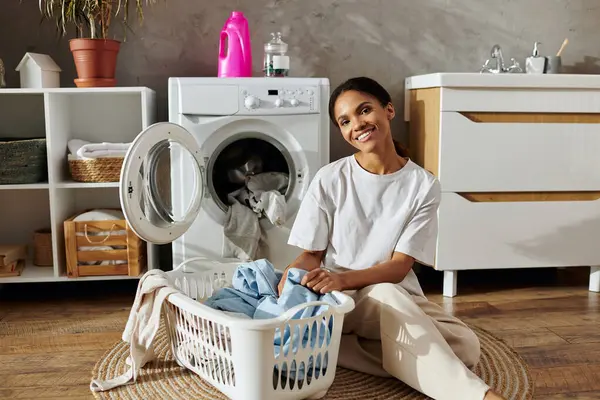 In a stylish apartment, a young woman is happily sorting laundry in a basket. — Stock Photo