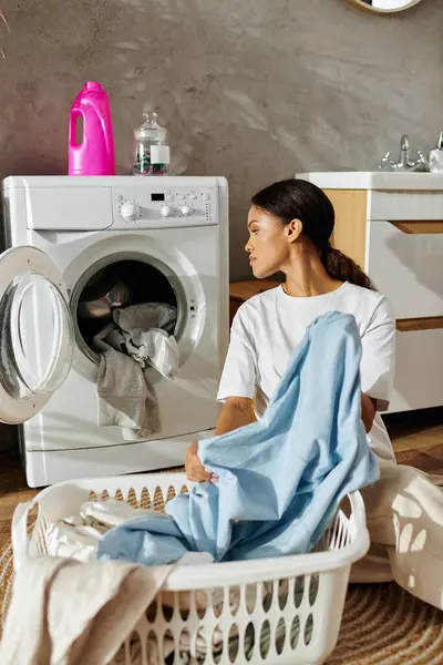 A young african american woman sorts laundry in her stylish apartment, embracing daily chores. — Stock Photo
