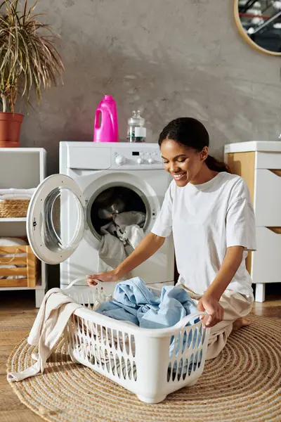 Eine junge Afroamerikanerin organisiert fröhlich ihre Wäsche in einem stilvollen Appartement. — Stockfoto