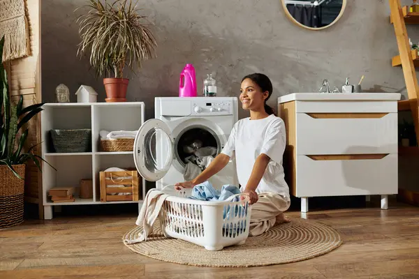 In einer modernen Wohnung legt eine junge Frau eine Pause ein, während sie Wäsche faltet, umgeben von sauberem Dekor. — Stockfoto