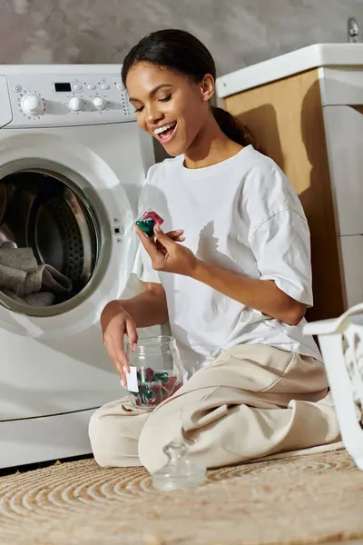 Lächelnde junge Frau sortiert Wäschekörbe, während sie in einer gemütlichen Wohnung auf dem Boden sitzt. — Stockfoto
