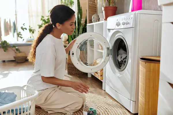 A young African American woman tidies up her laundry in a chic modern apartment. — Stock Photo