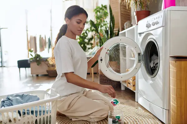 In a bright, modern apartment, a young African American woman efficiently tackles her laundry. — Stock Photo