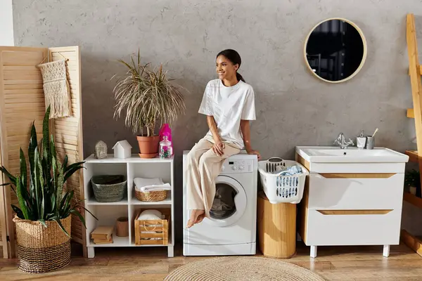 A young african american woman happily manages her house cleaning tasks in a stylish kitchen area. — Stock Photo