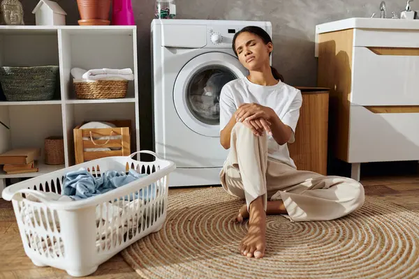 A young Black woman sits on a rug, handling her cleaning chores in a bright apartment. — Stock Photo