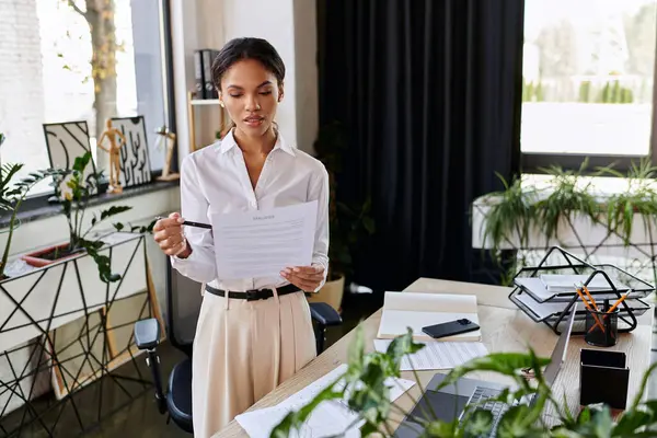 A young African American businesswoman reviews key documents in a stylish office. — Stock Photo