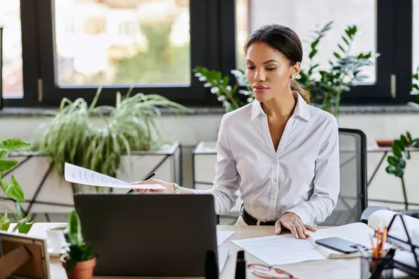 A professional businesswoman in a white shirt reviews documents at her desk while working. — Stock Photo