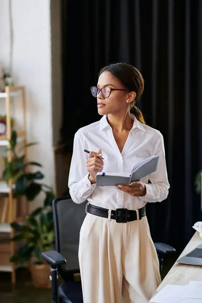 A young businesswoman in a white shirt reviews her notes while brainstorming solutions. — Stock Photo
