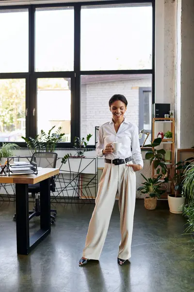 A young Black woman in a white shirt actively works in a plant-filled space. — Stock Photo