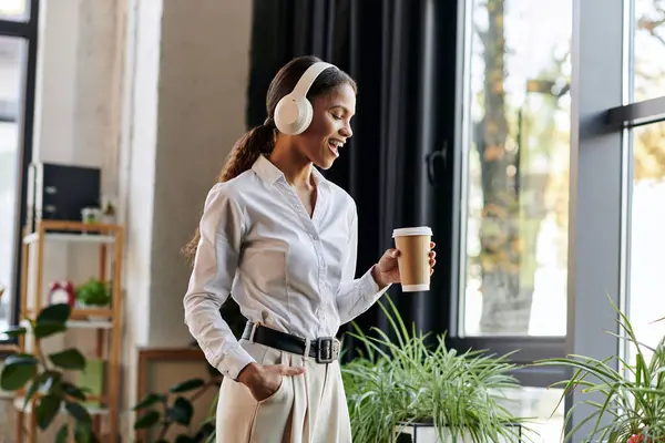 A young african american businesswoman enjoys her coffee while listening to music at work. — Stock Photo