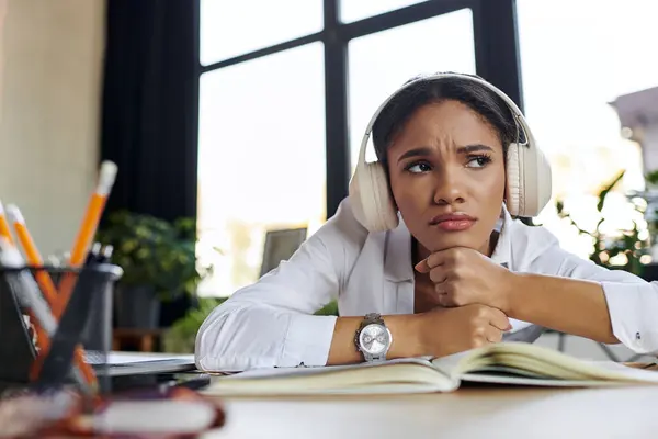 A young professional woman in a white shirt and headphones feeling sad in office — Stock Photo