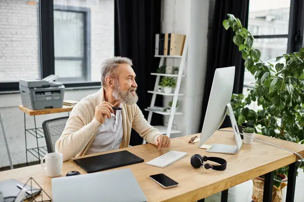 Mature man focused on his work at a desk in a bright and stylish office environment. — Stock Photo