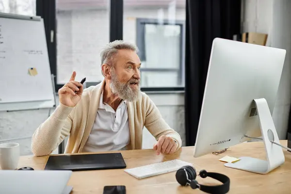 Mature man passionately shares ideas while seated at a desk in a bright office environment. — Stock Photo