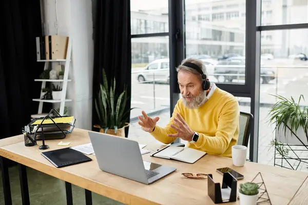 Handsome senior man actively participates in an online discussion during his workday. — Stock Photo