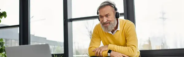 Handsome mature man with a beard participates in a video call at a bright workspace. — Stock Photo