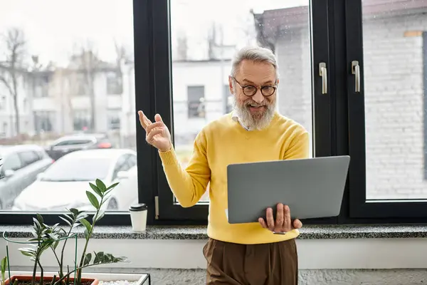 Handsome older man with a beard conducts a video call in a bright indoor space. — Stock Photo