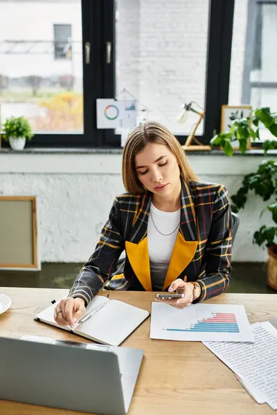 A attractive millennial woman reviews reports and charts while working diligently in her office. — стоковое фото