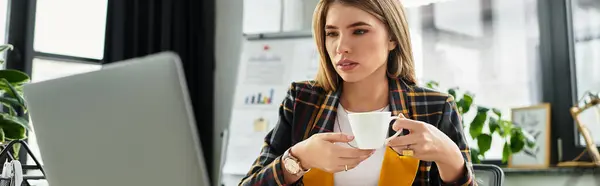 Focused businesswoman in a chic checkered blazer engages with her laptop while enjoying coffee, banner — Stock Photo