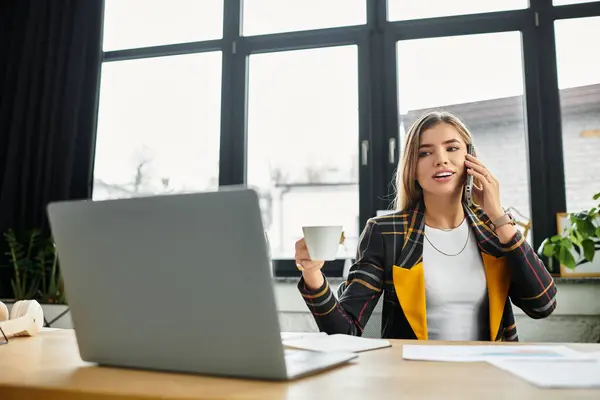 Atractivas charlas profesionales jóvenes por teléfono mientras disfruta del café en una oficina elegante. - foto de stock