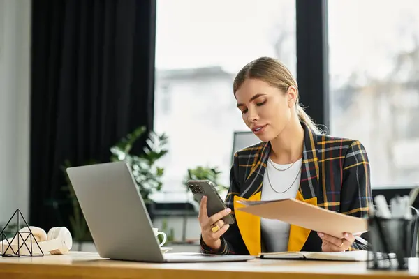 Attractive businesswoman engages with her smartphone while reviewing documents in a sleek office. — Stock Photo