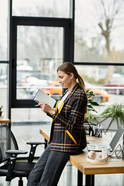 Focalizzata sui suoi compiti, una donna attraente recensisce le note in un blazer a scacchi alla moda. — Foto stock