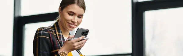 Привлекательная молодая женщина в стильном пиджаке проверяет свой смартфон во время работы, баннер — стоковое фото